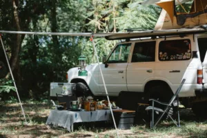 White SUV with extended side awning shading a campsite, hanging lantern and gear — ideal SUV camping awning setup