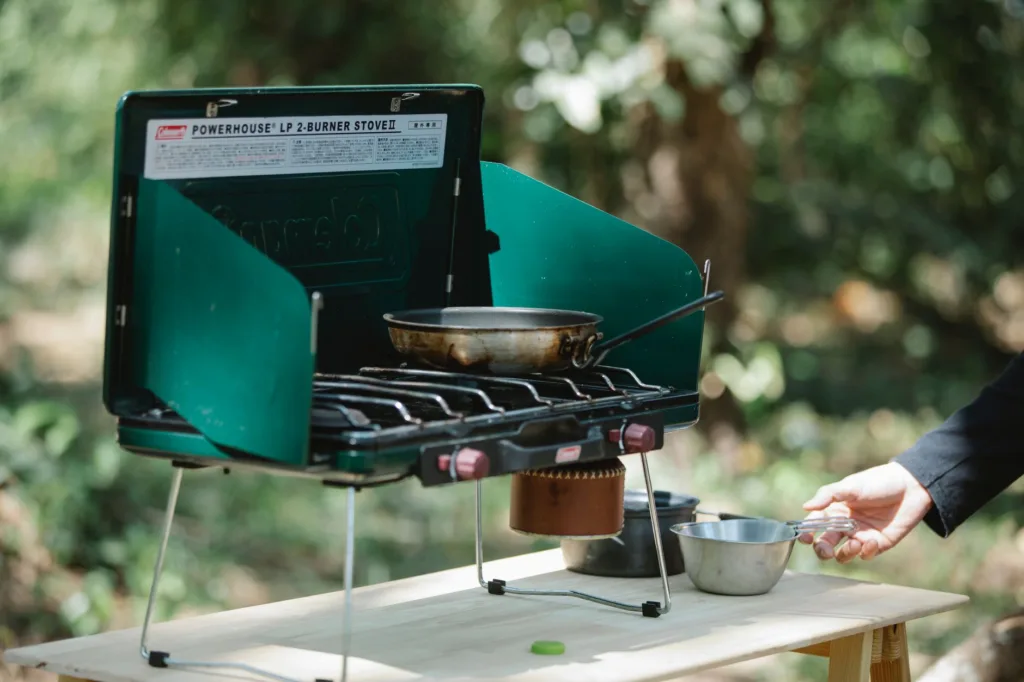 Green portable camping stove with skillet and metal pots, highlighting a compact camping cookware set