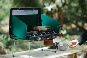 Green portable camping stove with skillet and metal pots, highlighting a compact camping cookware set