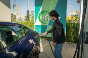 Person plugging a level two EV charger into a blue electric car at a home charging station