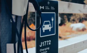 Tesla wall charger and cable beside a J-type charging station sign, illustrating Tesla to J adapter use