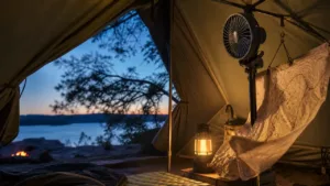 Rechargeable camping fan clipped inside a tent at dusk