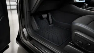 Custom-fit black car floor mat with blue trim installed beneath pedals