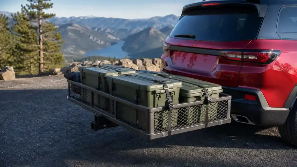 Hitch cargo carrier loaded with strapped storage bins behind an SUV