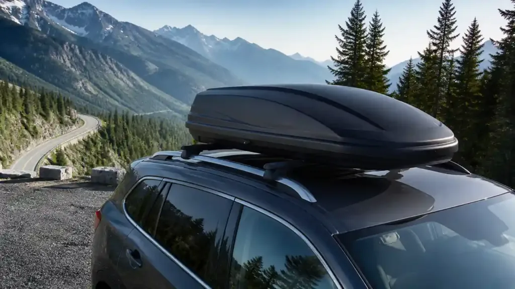 Streamlined roof cargo box secured on an SUV above a mountain road