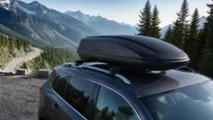 Streamlined roof cargo box secured on an SUV above a mountain road